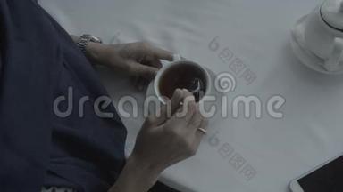 一个穿着蓝色裙子的女人用勺子在白色桌子上搅拌咖啡
